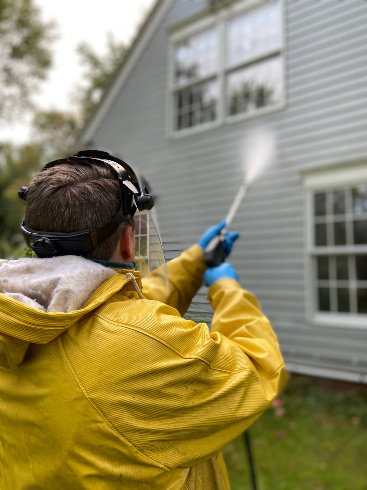Technician soft washing a house exterior siding